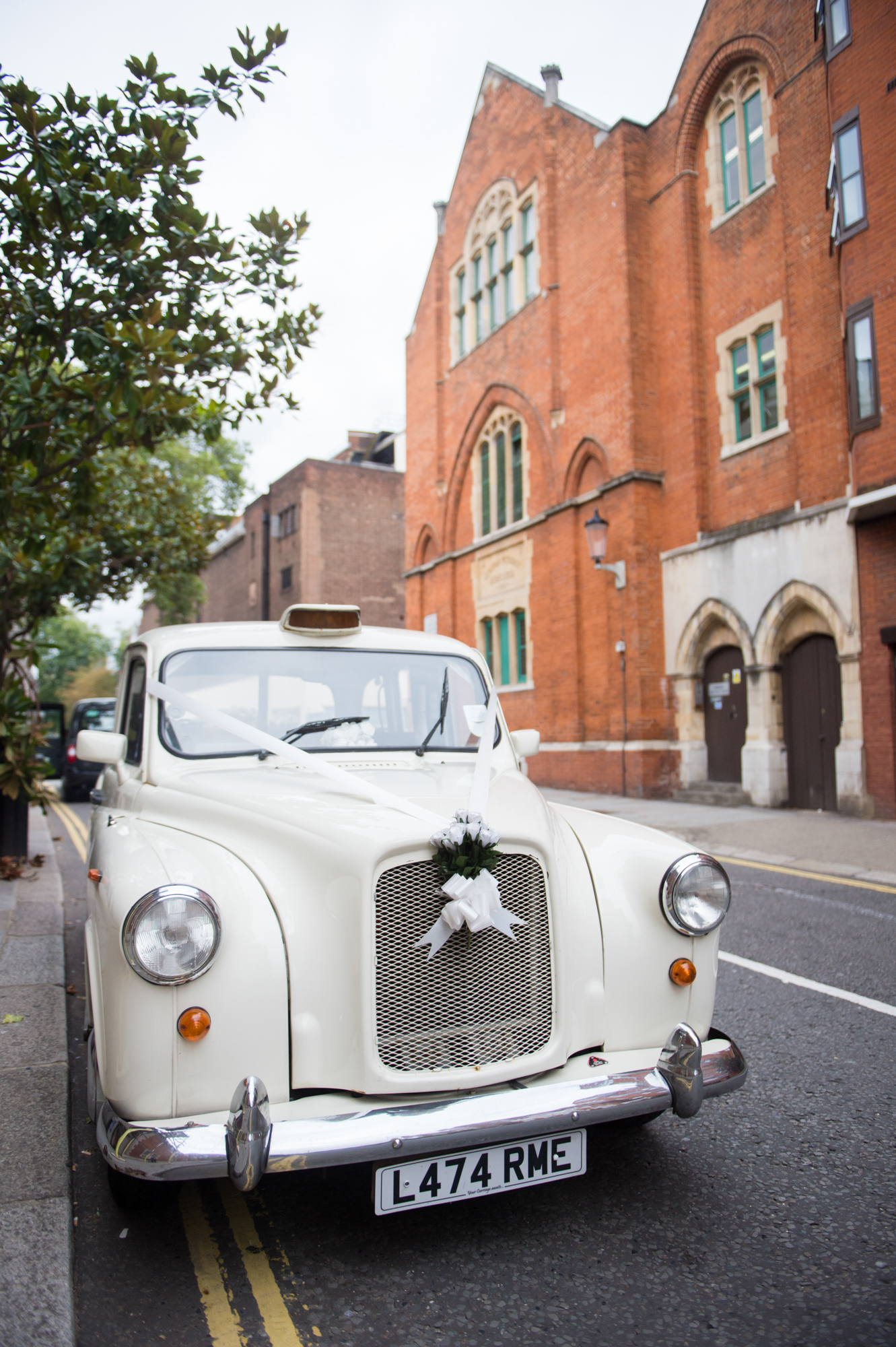 A white London taxi with a ribbon on it ready for a wedding